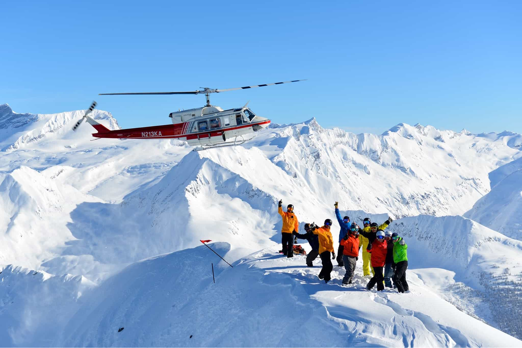 Heli-skiers celebrate and greet an incoming helicopter.