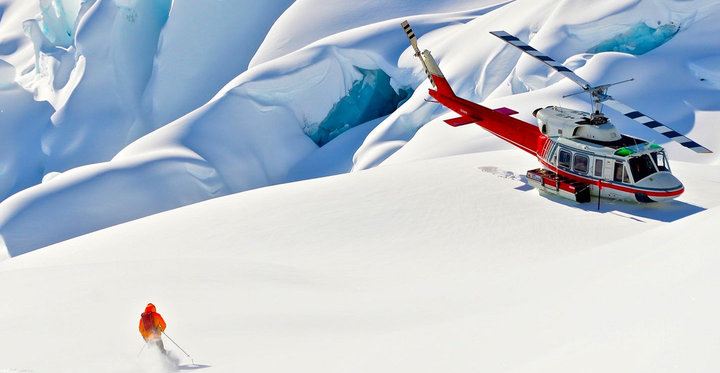 A skier approaches a heli-copter with CMH Heli-skiing